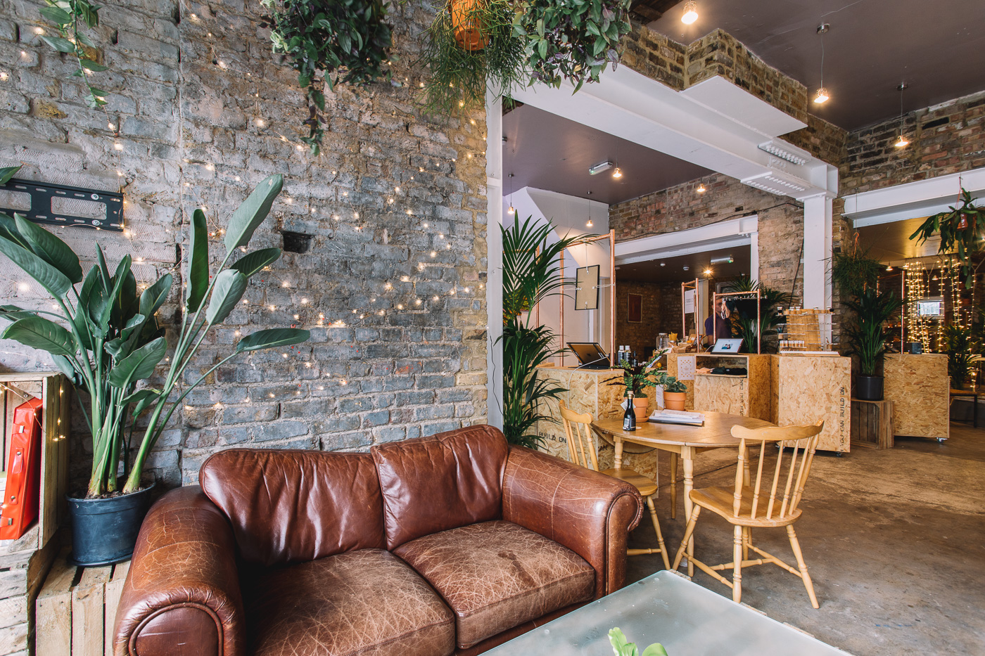 Communal lounge area with exposed brick, fairy lights and plants inside the converted Bethnal Green building