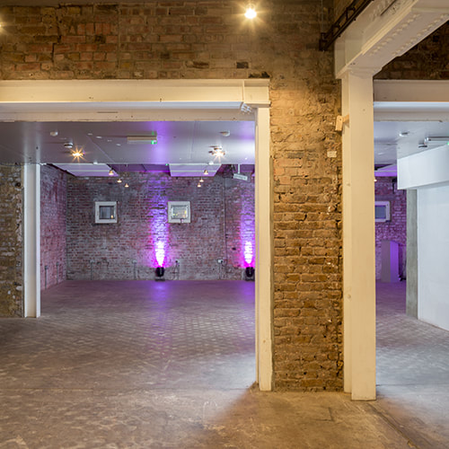 Corridor between commercial units with exposed brick columns and feature lighting
