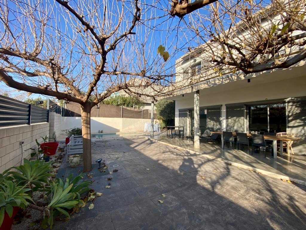 The house seen from the terrace, with the covered porch and the pergola of the mature tree