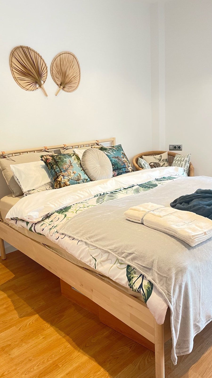Bedroom with pale timber flooring and woven wall pieces above the bed