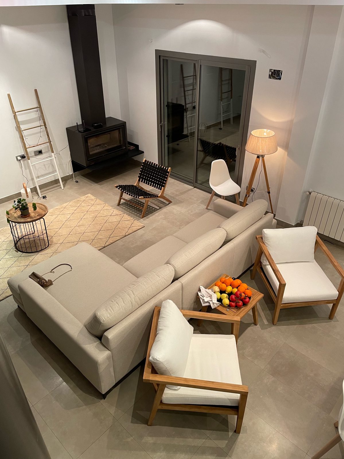 The living room seen from the mezzanine, with the wood-burning stove and the sliding doors to the terrace