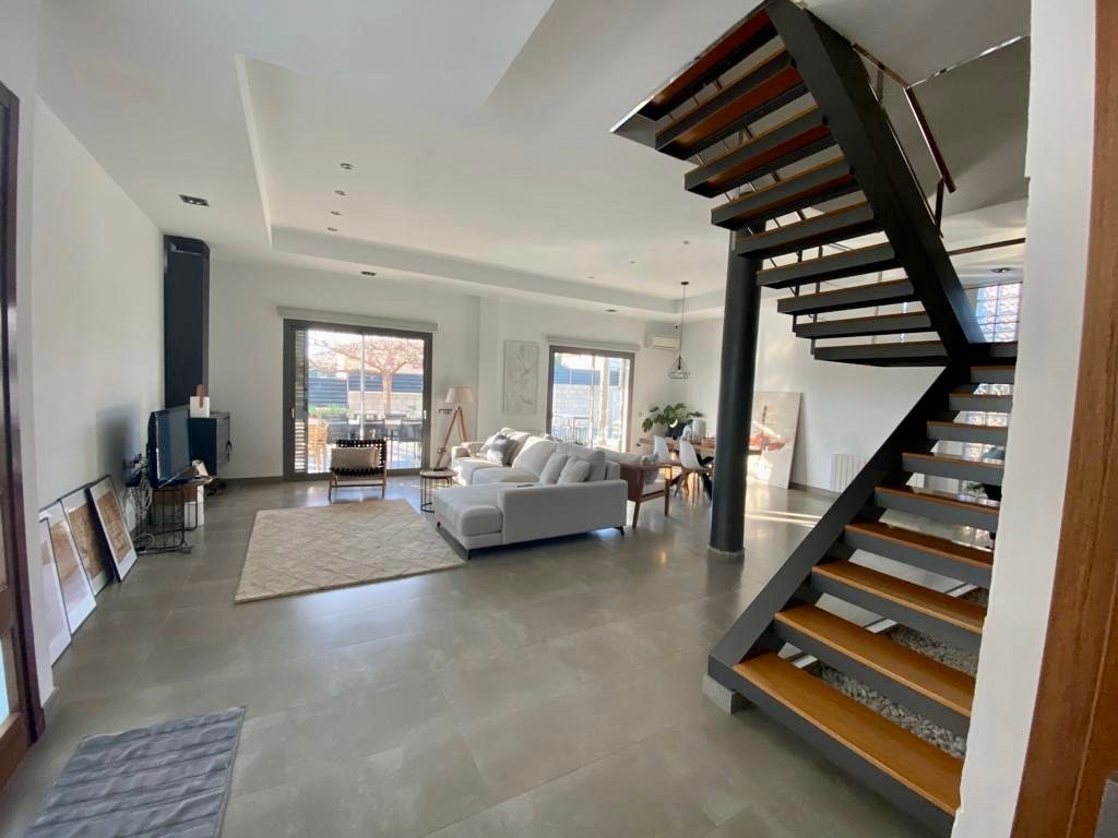 Living and dining space with the open staircase and full-height sliding doors onto the terrace