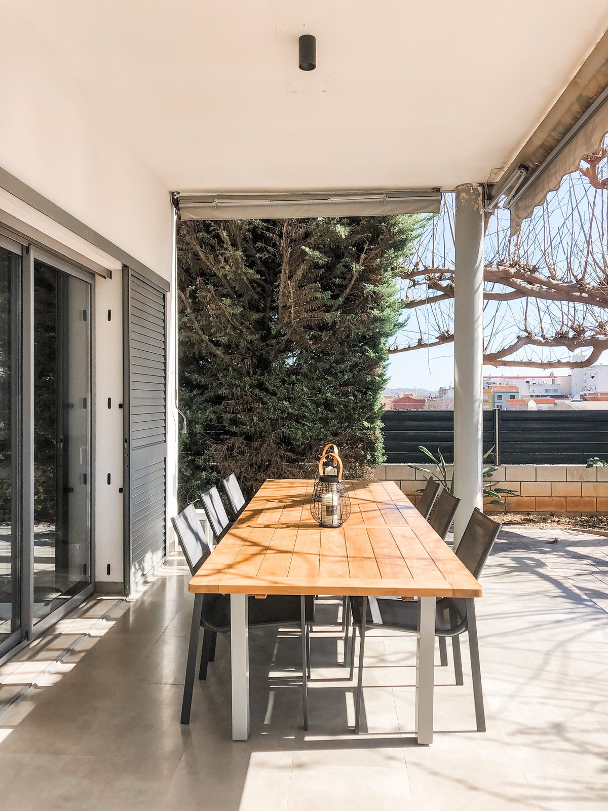 The long teak table under the pergola on the covered terrace