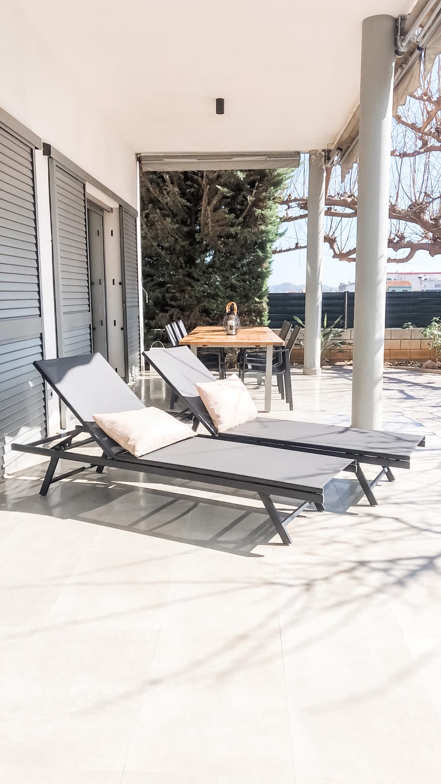 Loungers in the midday shade of the covered terrace, with the hills beyond