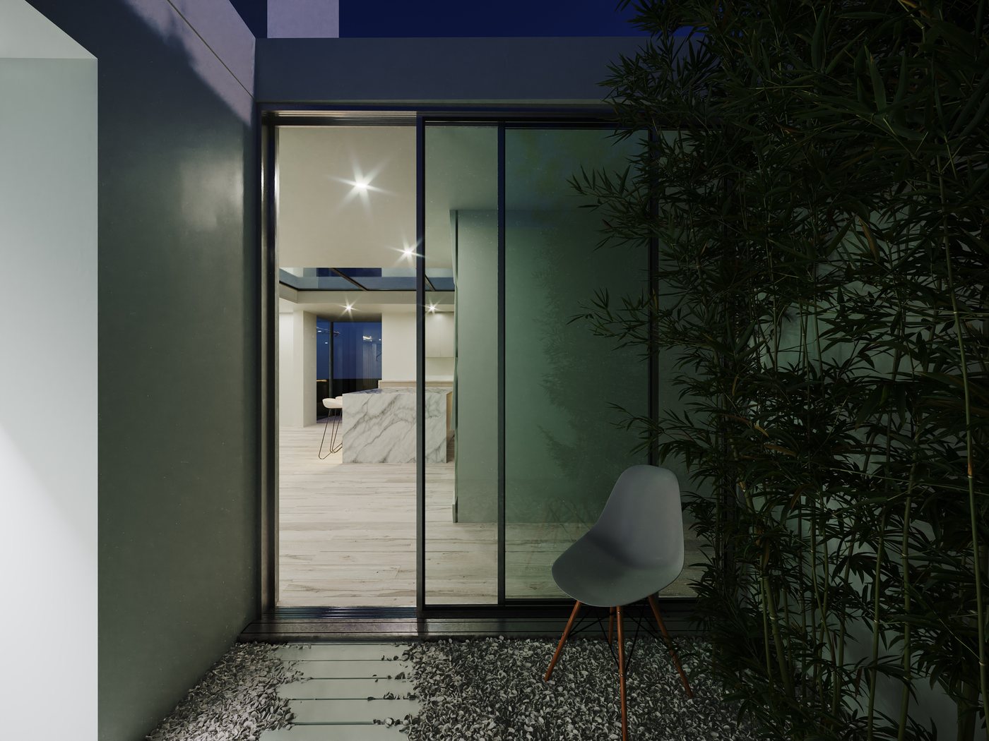 Internal courtyard at night — the lit interior glows through the floor-to-ceiling glass, the bamboo casting shadows against the white walls