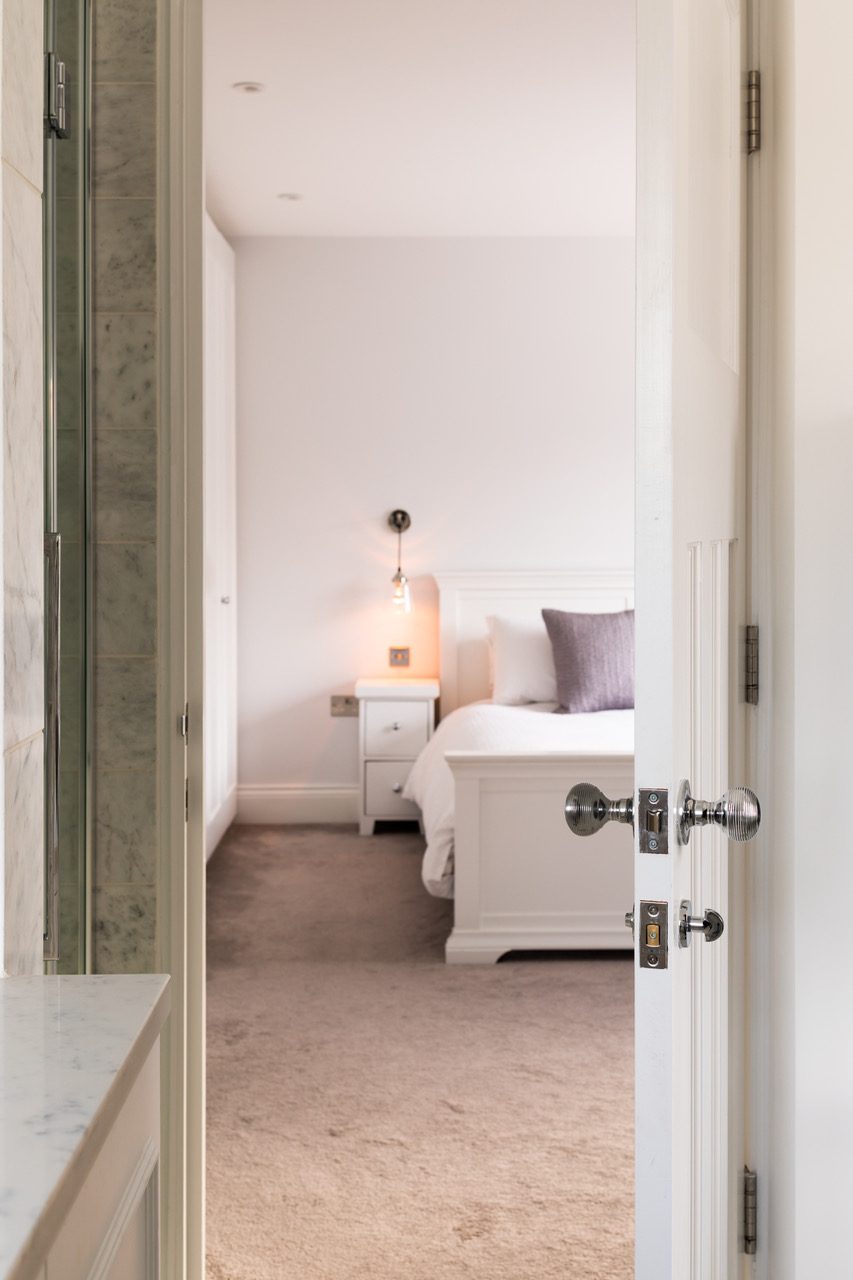 View from the en-suite bathroom through to the bedroom, with marble vanity surface and bedside pendant lighting