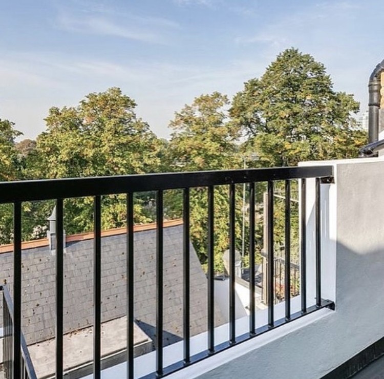 Ifield Road — private roof terrace with black steel balustrade looking out over the slate roofscape and treetops
