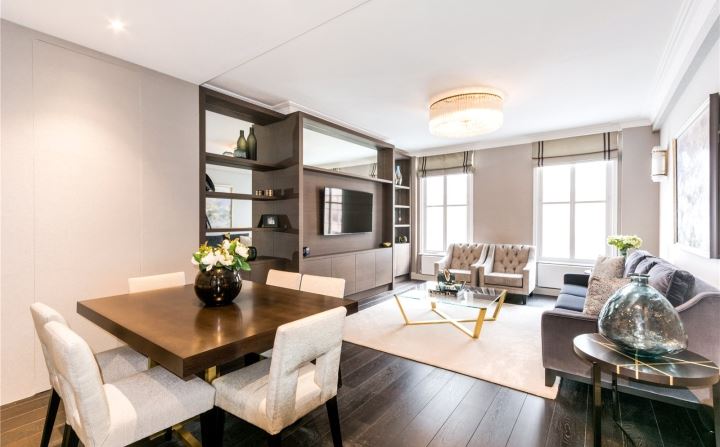 Open-plan dining and living space with dark oak flooring, statement chandelier and bespoke shelving