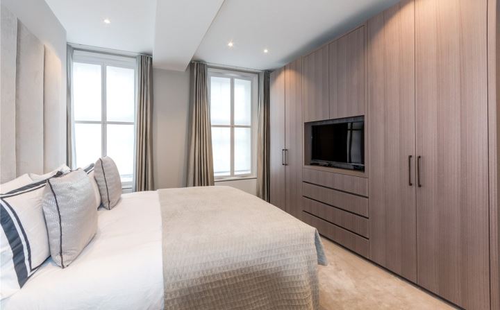 Guest bedroom with upholstered headboard, fitted wardrobes and integrated TV unit