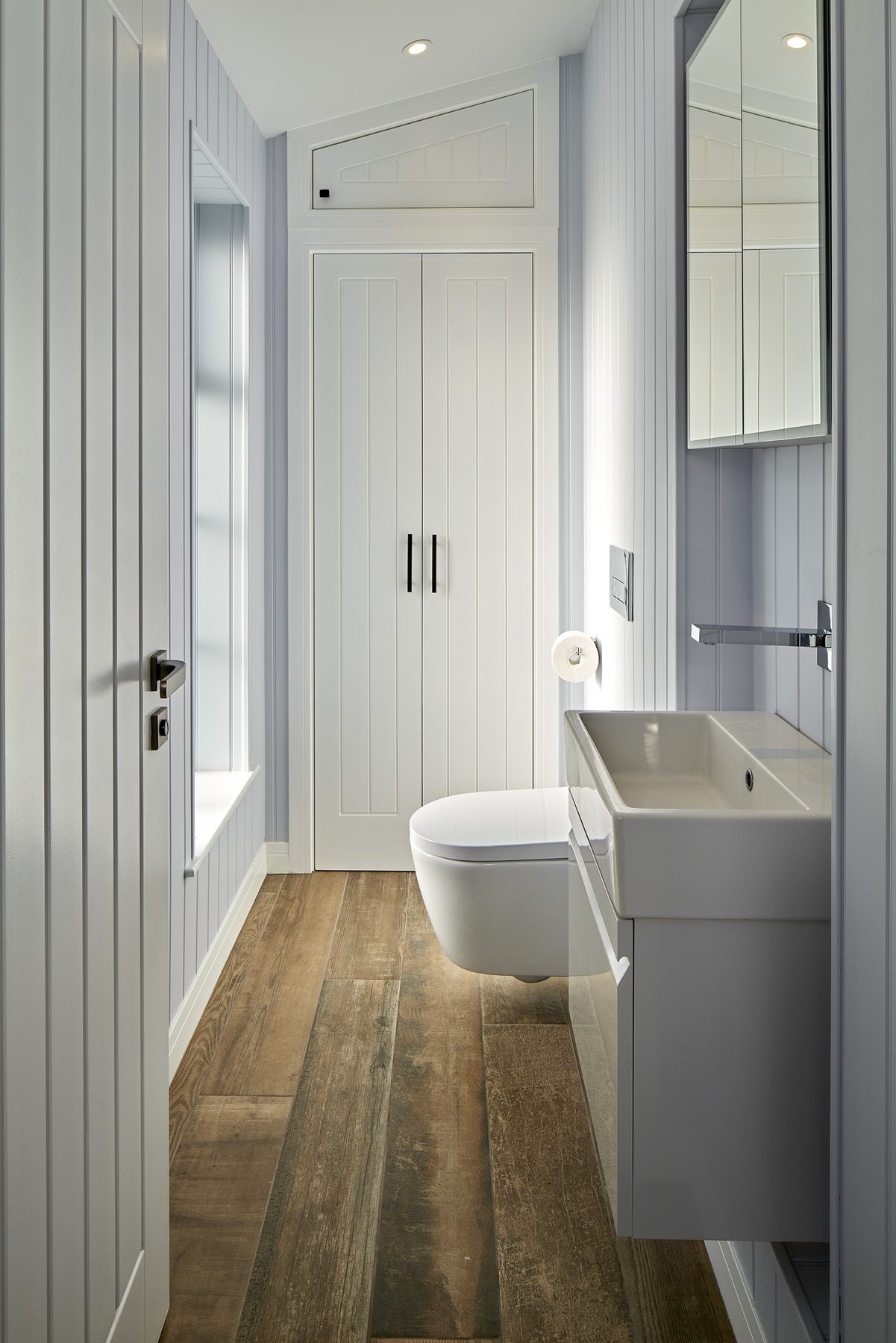 Shower room with tongue-and-groove panelling, wall-hung sanitaryware and reclaimed timber flooring