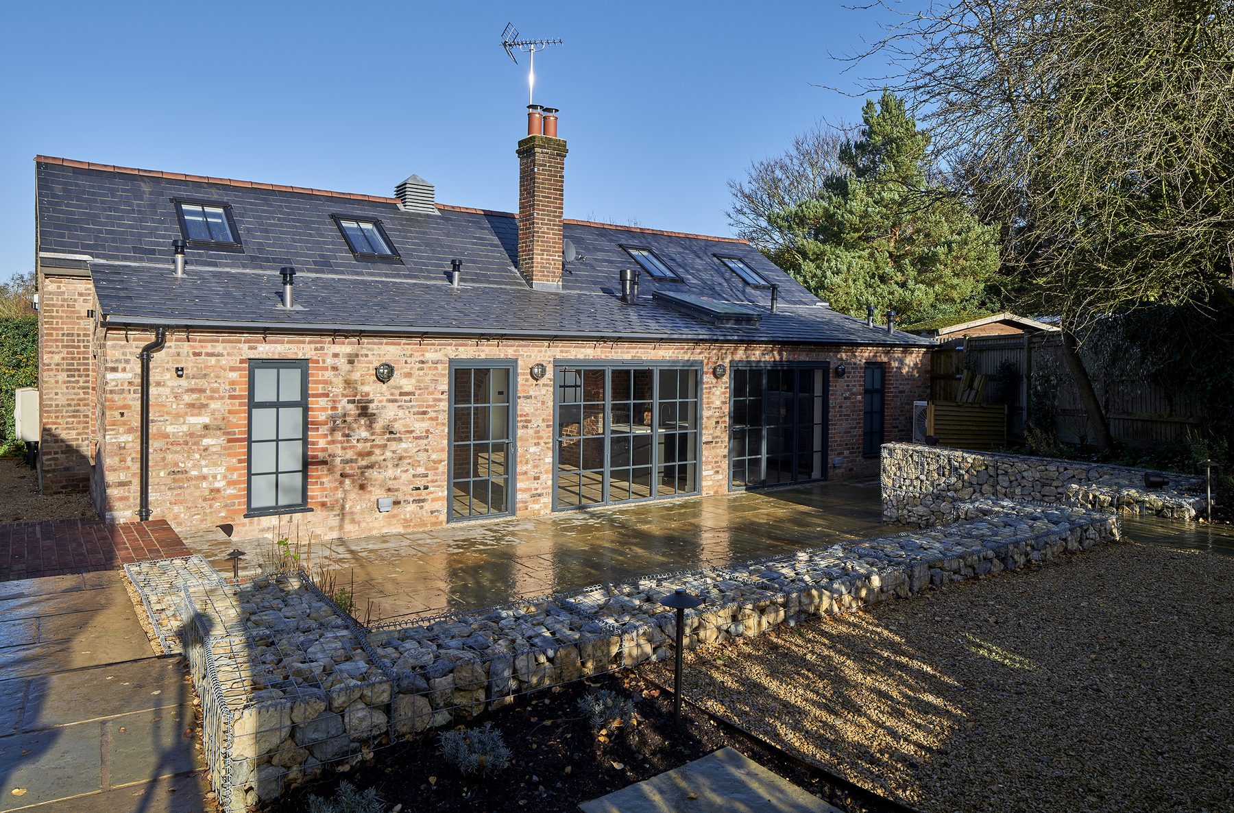 Rear garden of The Old Forge with gabion retaining walls, stone paved terrace and gravel beds