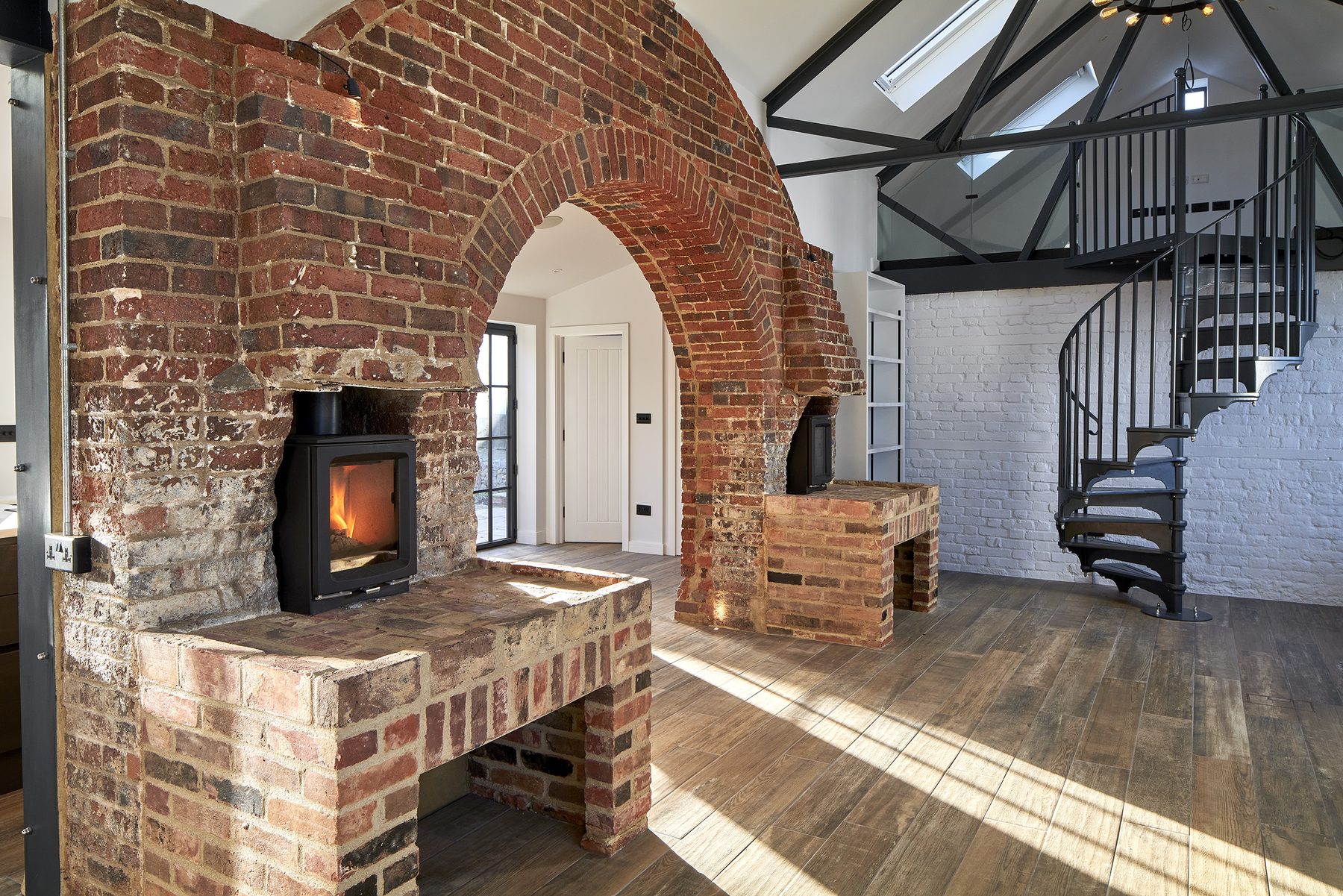 The forge arch seen from the living space, with the black spiral staircase and exposed steel trusses beyond